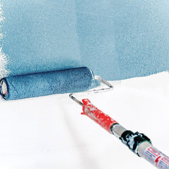 Paint roller applying blue paint to white wall