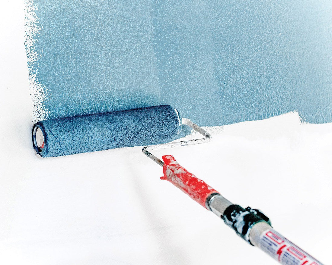 Paint roller applying blue paint to white wall
